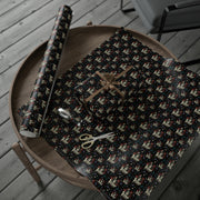 Svengoolie wrapping paper roll and a folded sheet on a round wooden table with a bow-tied gift and gold scissors.