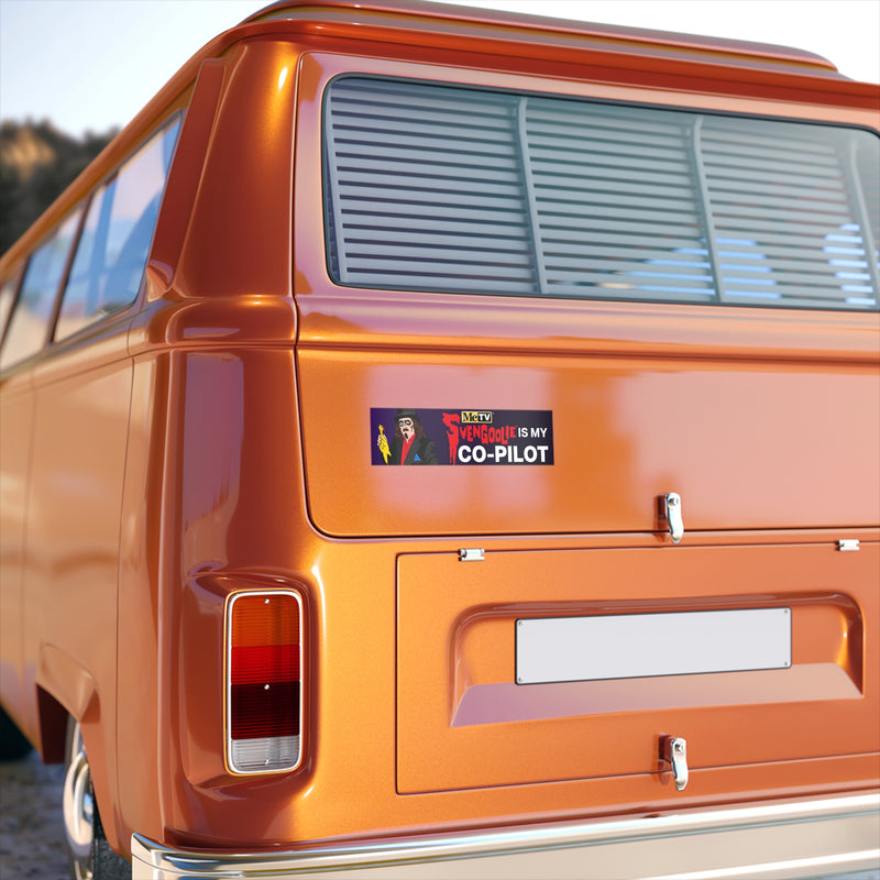 Rear of an orange van showing the Svengoolie Is My Co-Pilot bumper sticker on the back panel above the license plate.