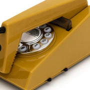 Close-up of the mustard phone's rotary dial with white number buttons and a chrome finger plate, viewed at an angle