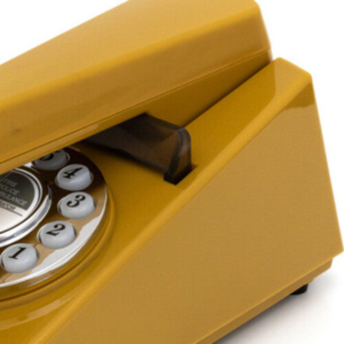 Angled close-up of the mustard phone's rotary dial showing the numbers 1 through 5 next to the handset cradle