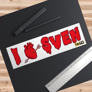 Overhead close-up of the I Heart Sven bumper sticker on a black surface beside a pen and ruler that show its size.