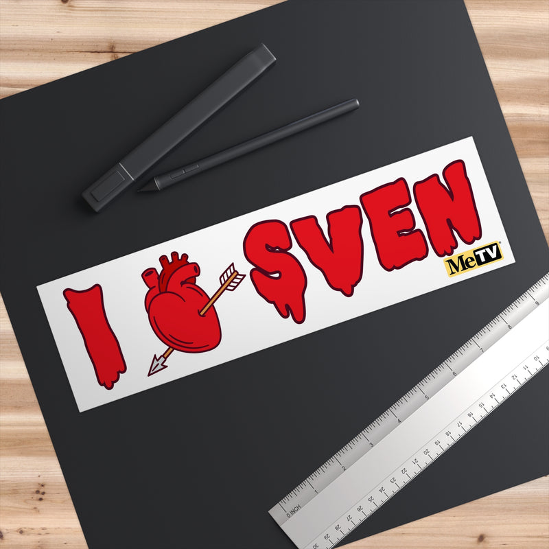 Overhead close-up of the I Heart Sven bumper sticker on a black surface beside a pen and ruler that show its size.