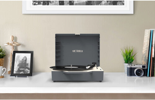 Gray Victrola Re-Spin record player open on a desk with a record on the platter and the text 'VICTROLA' in silver on the lid
