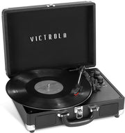 Black suitcase-style turntable with its lid open and a vinyl record on the platter, featuring the text 'VICTROLA' in white on the inside lid.