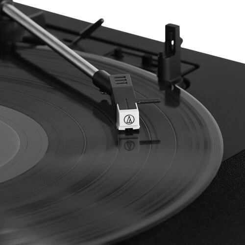 Close-up of the silver tonearm and white Audio-Technica cartridge positioned over a black record on the turntable.