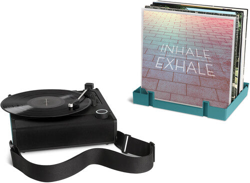 Black record player with shoulder strap beside a blue record crate holding albums, including one with the text 'INHALE EXHALE' on its cover.