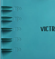 Close-up of the blue lid showing five record storage slots and part of the 'VICTROLA' text in black.