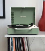 Front view of basil green Victrola record player with lid open, showing a black record on the turntable and record storage slots