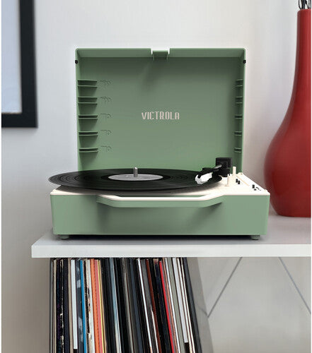 Front view of basil green Victrola record player with lid open, showing a black record on the turntable and record storage slots