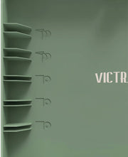 Close-up of record storage shelves and embossed record icons on the lid of basil green record player, with cream lettering reading 'VICTR' partly cropped.