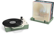 Basil green record player beside a matching stand holding vinyl albums upright in its slots.
