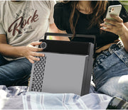 Two people sitting outdoors holding the gray record player on their laps, with the man wearing a gray Rock Vinyl graphic t-shirt