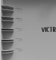 Inside gray lid of record player with five record shelves on the left and partially visible text 'VICTR' in black