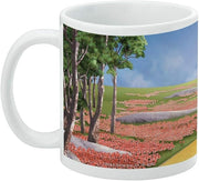Left side of the white Tin Man mug showing a tree-lined poppy field, gray stones, and part of the yellow brick road.
