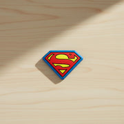 Single Superman shield bag clip resting on a light wood surface.