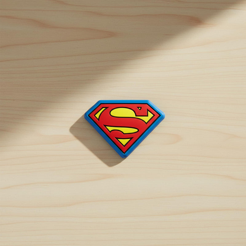 Single Superman shield bag clip resting on a light wood surface.