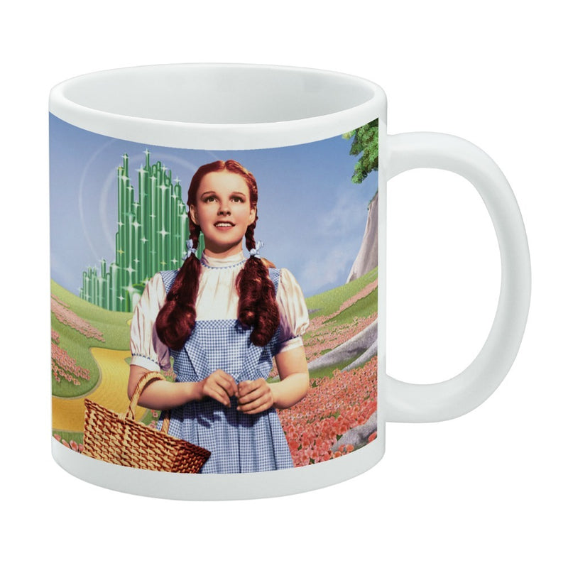 White mug featuring Dorothy in a blue gingham dress and braids beside a picnic basket, with the Emerald City and a poppy field behind her.