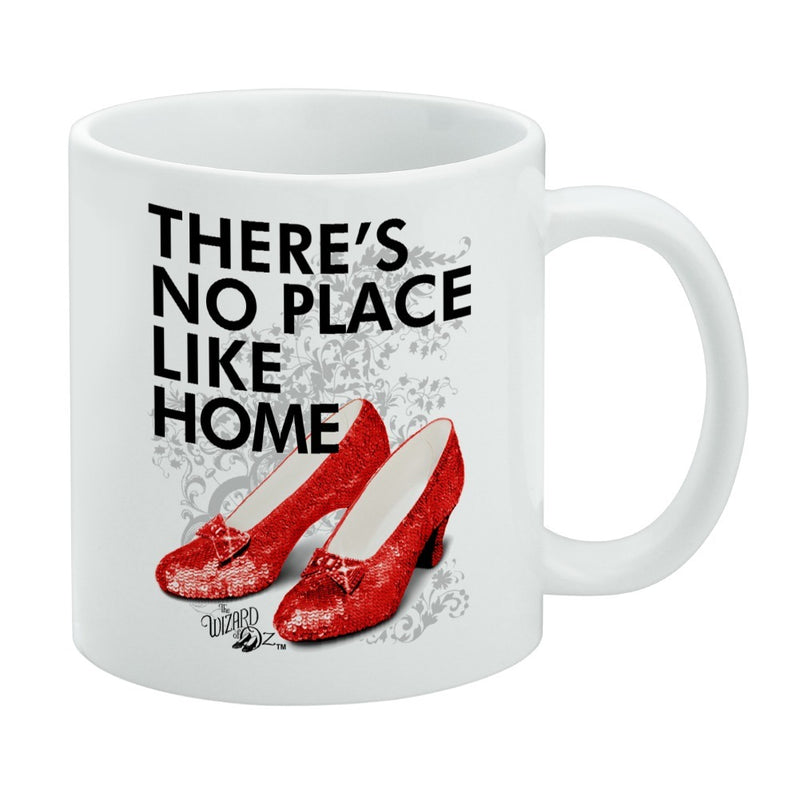 White ceramic mug featuring a pair of sparkly red sequined ruby slippers with the text 'THERE'S NO PLACE LIKE HOME' in black above them.