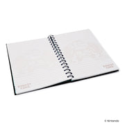 Open view of the spiral notebook showing lined pages with faded pixel-art Donkey Kong graphics and the text 'DONKEY KONG' in the corners.