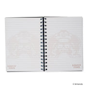 Open notebook to two lined pages with faint Donkey Kong pixel artwork and a small 'DONKEY KONG' logo in the lower corners.