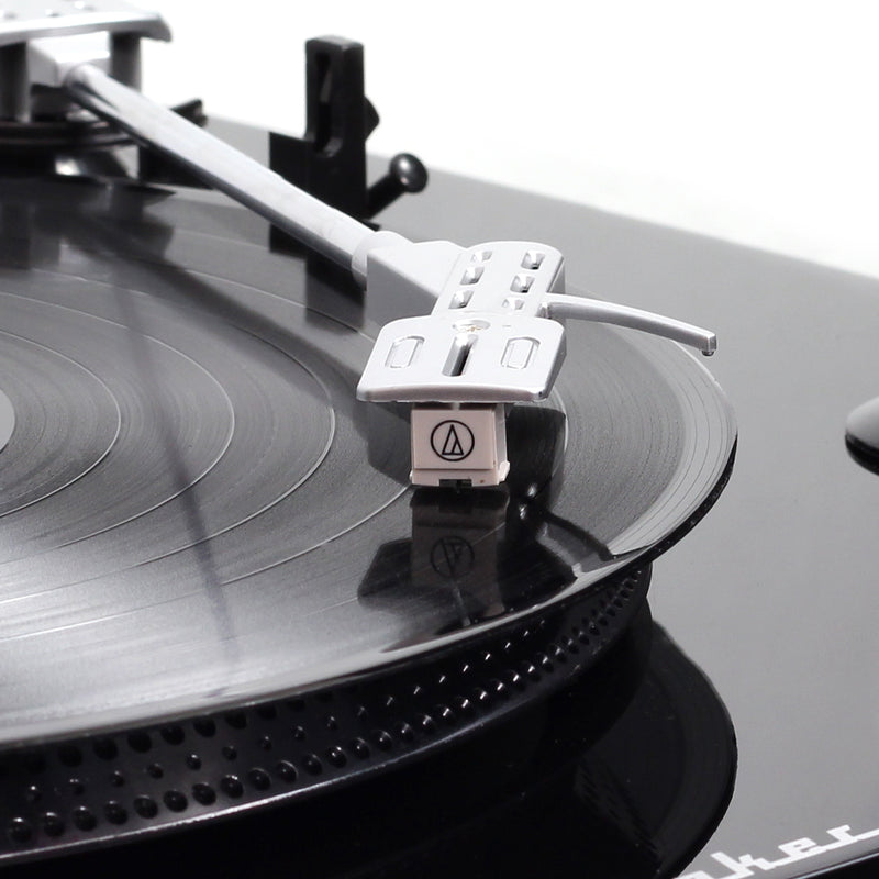 Close-up of the silver tonearm and white Audio-Technica cartridge resting on a black vinyl record on the Studebaker turntable.