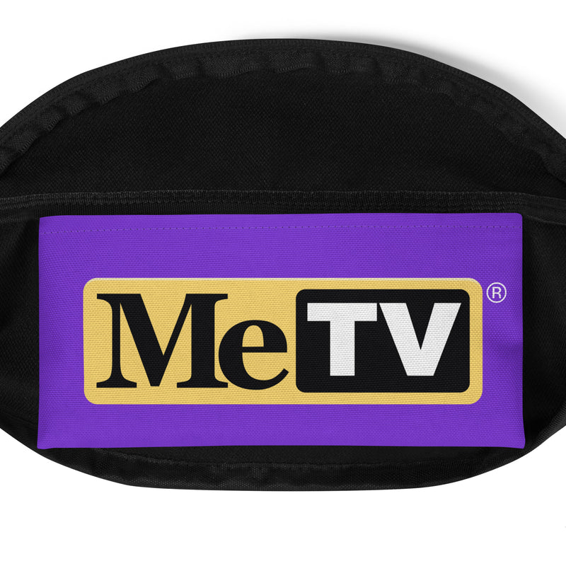 Front view of black fanny pack with a purple panel featuring the MeTV logo with the text 'MeTV' in black and white on a yellow badge with a registered mark.