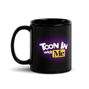 Black glossy ceramic mug with the Toon In with Me logo in white and yellow with a purple glow on the side facing the viewer, handle on the left.