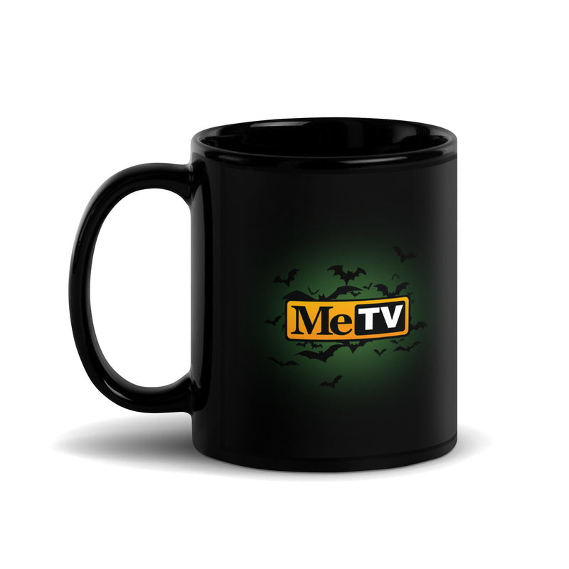 Black glossy ceramic mug with a green glow and a flock of bats around the MeTV logo, which has the text 'MeTV' in black and white on a yellow badge.