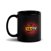 Black ceramic mug with a handle on the left, featuring the MeTV logo with the text 'MeTV' in yellow and black on a red glow surrounded by black bats.