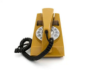 Mustard retro trim phone with a silver rotary dial and coiled black cord, viewed straight on from the front