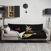 Lifestyle view of black Svengoolie throw blanket draped over a gray sofa featuring a pale reaching hand and a yellow chicken with red accents.