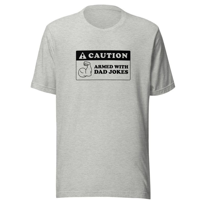 Heather gray t-shirt featuring a black caution sign graphic with the text 'CAUTION' and 'ARMED WITH DAD JOKES' beside a flexing arm icon.
