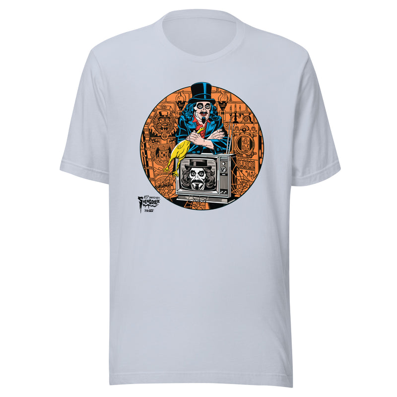 Light Blue t-shirt featuring Svengoolie holding a rubber chicken, by a TV with Orange circle border. Svengoolie logo at lower left.