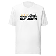 White short-sleeved unisex t-shirt featuring a three-of-five star rating graphic with the text 'Almost AWARD-WINNING DAD JOKES' in black on the chest