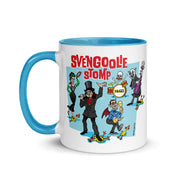 White mug with blue handle and interior featuring a cartoon band of Svengoolie characters with red SVENGOOLIE STOMP text and Svengoolie logo to left