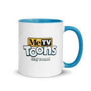 White ceramic mug with blue handle and blue interior featuring the MeTV Toons logo with the text 'Stay Tooned' in black below it.