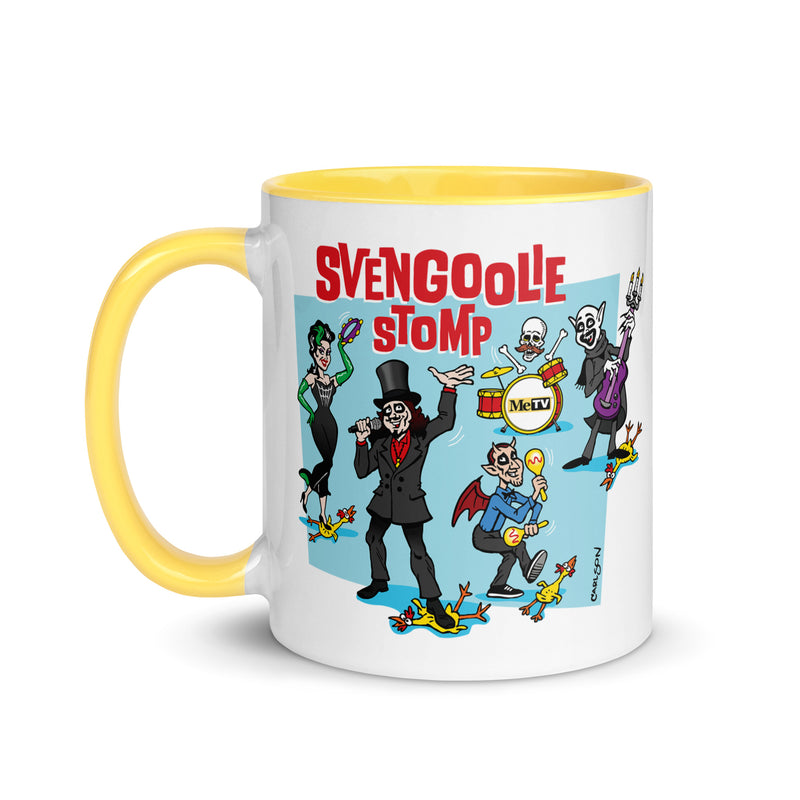White mug with yellow handle and interior featuring a cartoon band of Svengoolie characters with red SVENGOOLIE STOMP text and Svengoolie logo to left