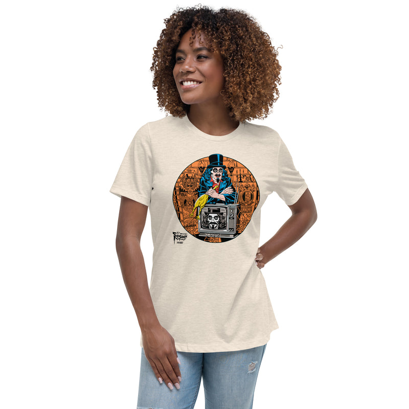 Model wearing Tan t-shirt featuring Svengoolie holding a rubber chicken, by a TV with Orange circle border. Svengoolie logo at lower left.