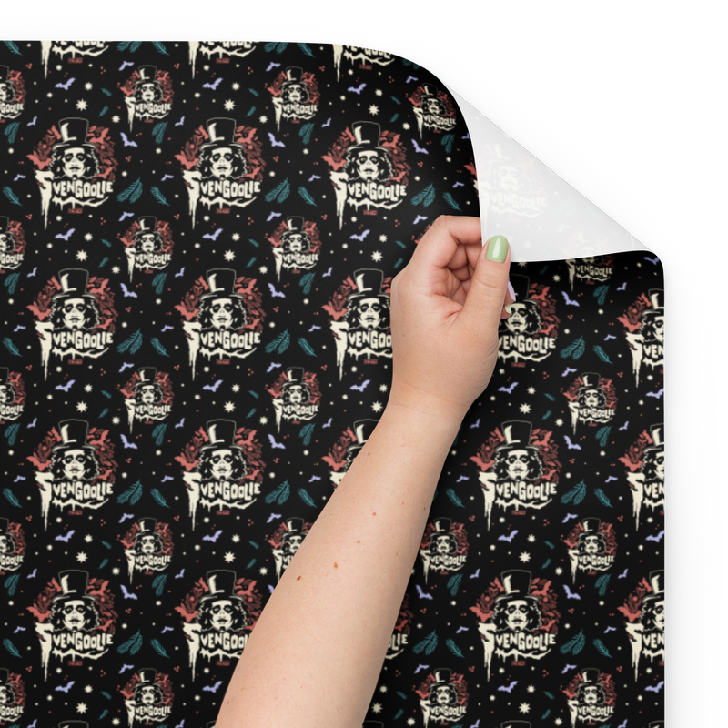 Close-up of black wrapping paper with a repeating Svengoolie face logo and the text 'Svengoolie' in cream below it, with the white reverse side showing at the corner.