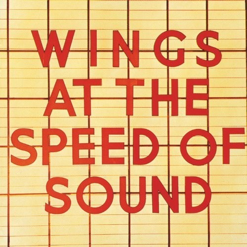 Album cover for Wings At The Speed Of Sound: red block letters reading 'WINGS AT THE SPEED OF SOUND' over a pale yellow grid background.