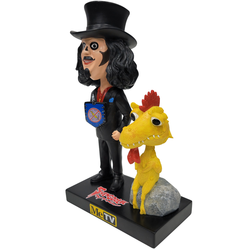 Right facing 3/4 view of Svengoolie bobblehead in black top hat, black suit, and blue shield with red emblem, beside yellow Kerwyn bobblehead on gray rock; base reads "Svengoolie" and "MeTV".