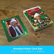 Close-up of a king of clubs card from Christmas Vacation playing cards showing Clark Griswold smiling in a Santa hat, next to the card deck.