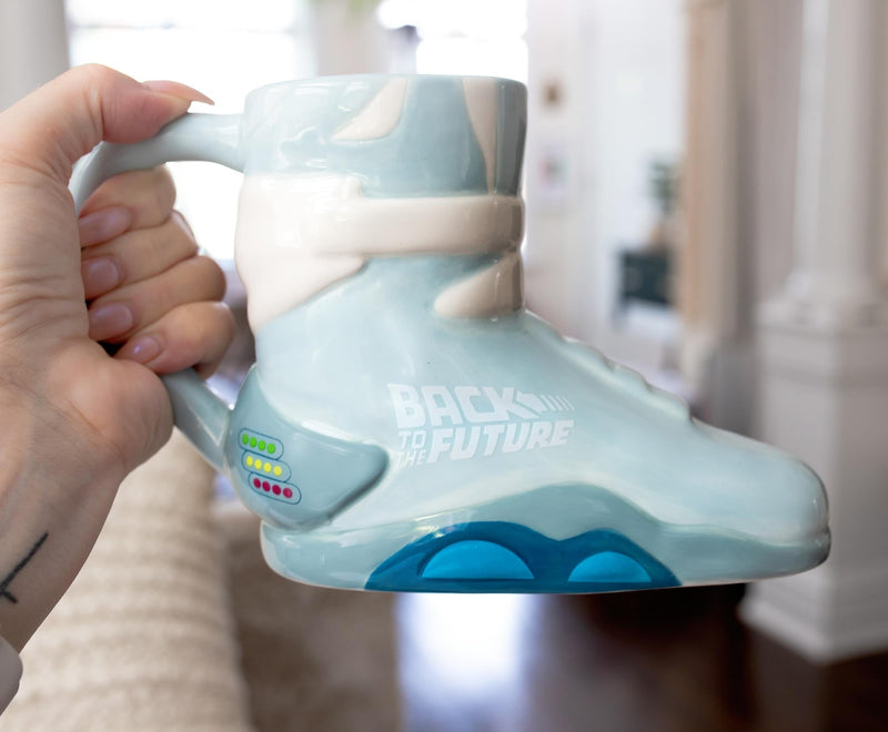 Light blue ceramic mug sculpted like a Back to the Future Nike sneaker, with white 'BACK TO THE FUTURE' printed on the side and blue sole accents.