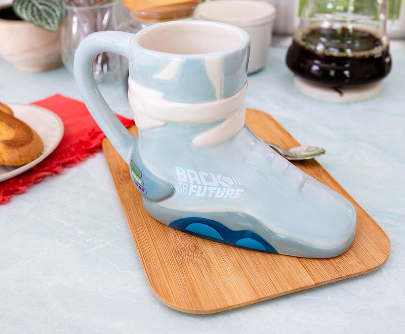 Angled view of light blue sneaker-shaped ceramic mug with white laces and blue sole, featuring the text 'BACK TO THE FUTURE' in white on its side.