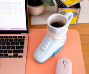 Angled view of light gray ceramic mug shaped like a Back to the Future Marty's sneaker with 'BACK TO THE FUTURE' text in white on the side.