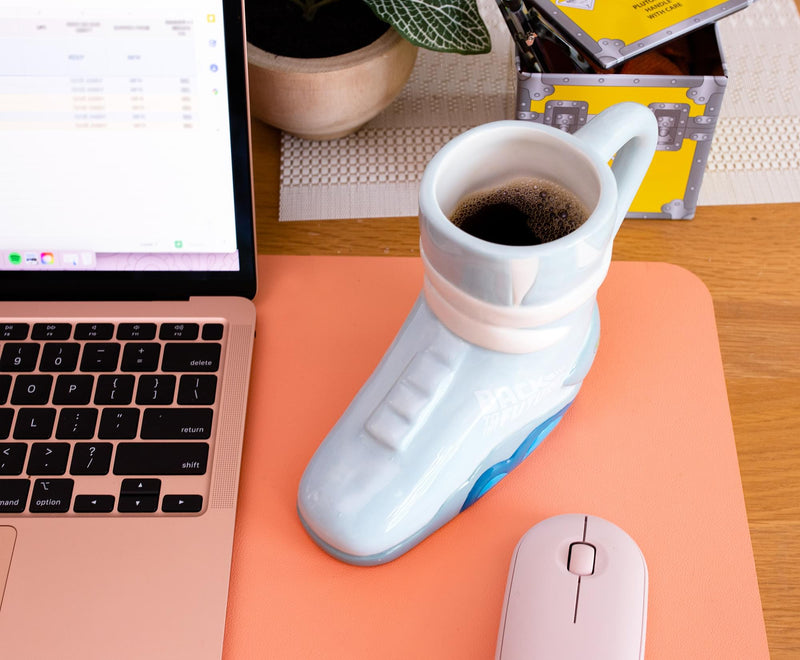 Angled view of light gray ceramic mug shaped like a Back to the Future Marty's sneaker with 'BACK TO THE FUTURE' text in white on the side.