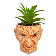 Tan ceramic planter shaped like Freddy Krueger's face from A Nightmare on Elm Street, holding an artificial succulent in its top opening.