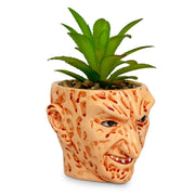Side view of the Freddy Krueger face planter showing its profile, sculpted ear, and the artificial succulent inside.