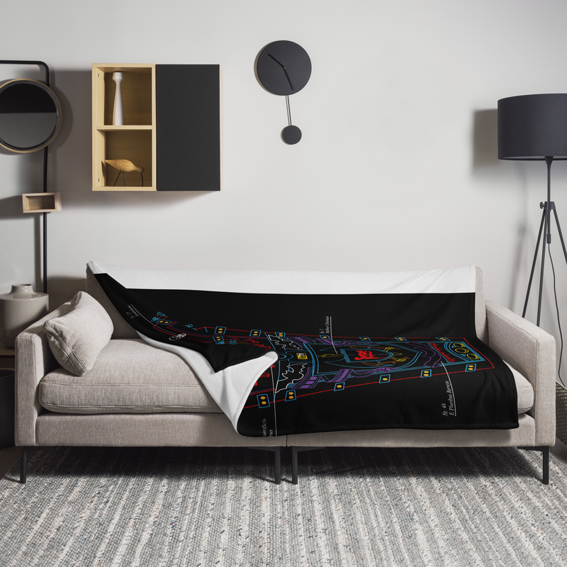 Black throw blanket with neon line art in blue, purple, yellow, and red, draped over a beige sofa.