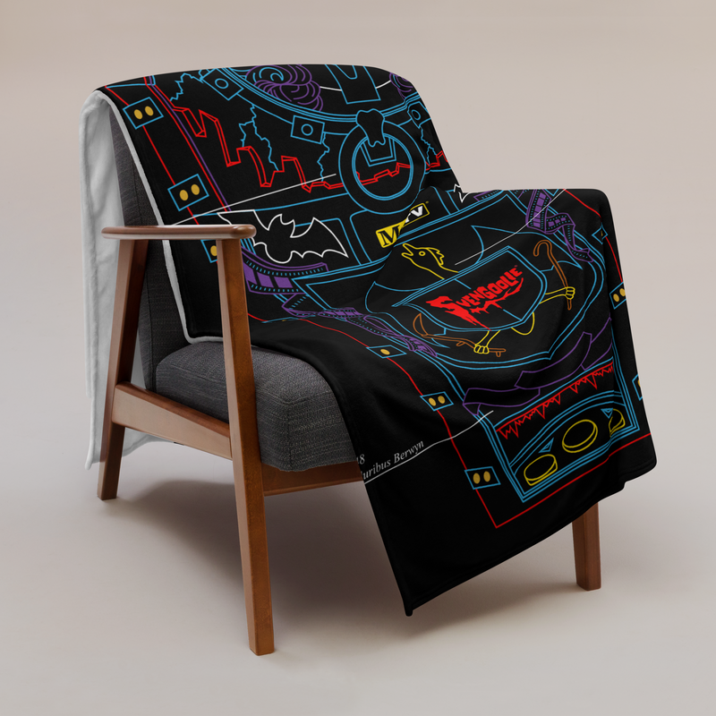 Black throw blanket with blue, red, and purple line art of a coffin, top-hat skeleton, and 'Svengoolie' logo. draped over a wooden armchair